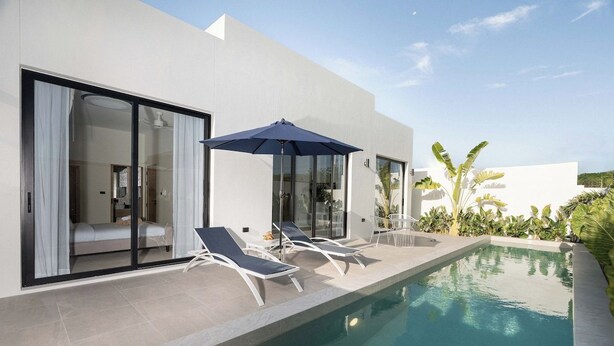 A modern poolside area with a clear pool, sun loungers, and a large umbrella. - Staylar Pool Villa - Bangtao, Phuket C1 (Phuket, Bangtao)