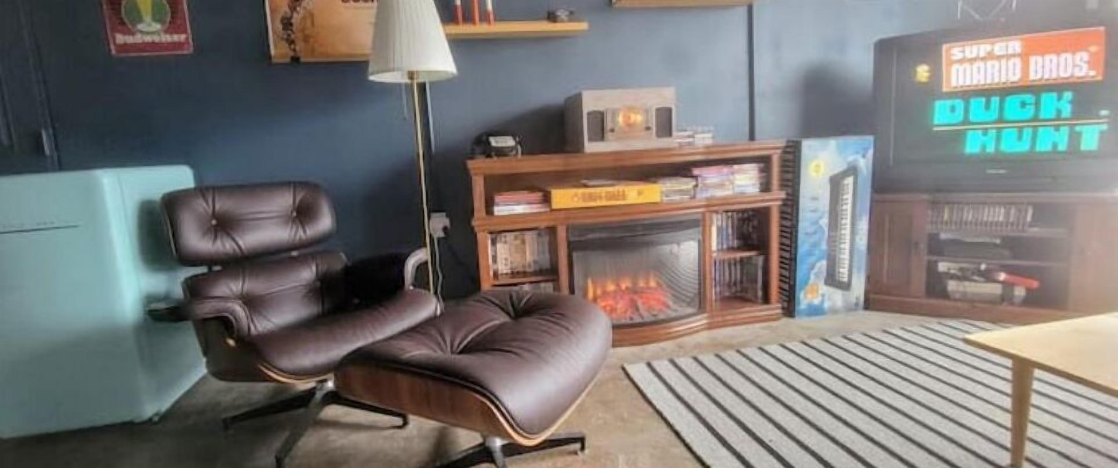 A living room with a leather recliner, a fireplace, a TV displaying 'SUPER MARIO BROS. DUCK HUNT', and a bookshelf.