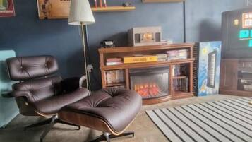 A living room with a leather recliner, a fireplace, a TV displaying 'SUPER MARIO BROS. DUCK HUNT', and a bookshelf.