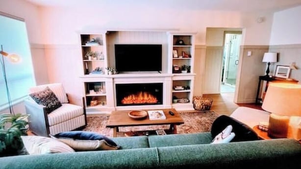 A living room with a fireplace, a television, and a sofa. - Downtown Designer Duplex close to Beach! Spa Tub, Sunroom, Game Room, EV & more! (Long Beach)