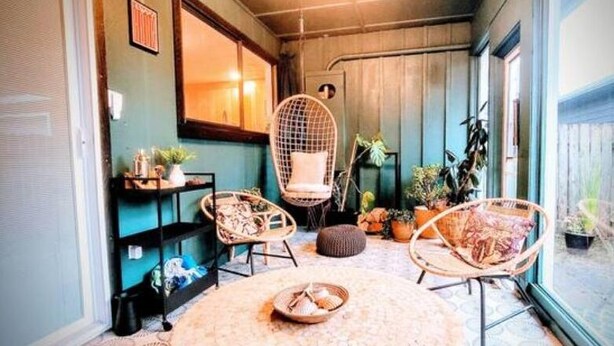 A cozy indoor space with wicker chairs, a round table, and potted plants. - Downtown Designer Duplex close to Beach! Spa Tub, Sunroom, Game Room, EV & more! (Long Beach)