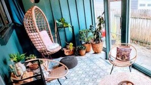 A cozy patio with wicker chairs, a small table, and potted plants. - Downtown Designer Duplex close to Beach! Spa Tub, Sunroom, Game Room, EV & more! (Long Beach)