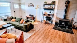 A modern living room with a green sofa, a coffee table, and a fireplace. - Downtown Designer Duplex close to Beach! Spa Tub, Sunroom, Game Room, EV & more! (Long Beach)