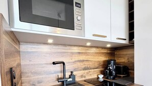 A modern kitchen with a built-in microwave, a sink, and a coffee maker.
