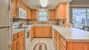 Una cocina con armarios de madera, un refrigerador blanco, un microondas y una estufa.