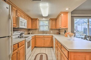 Una cucina con mobili in legno, un frigorifero bianco, un forno a microonde e un fornello.