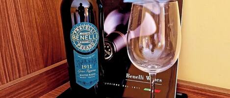 Una botella de vino Benelli, una copa de vino y un sacacorchos sobre una bandeja con un paño verde.