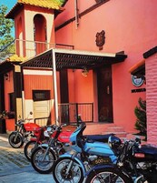 Una fila de motocicletas estacionadas frente a un edificio con fachada roja y un balcón.