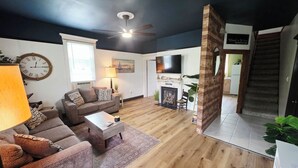 A living room with a sofa, coffee table, lamp, fireplace, and a TV. - Charming 1850s Victorian on the Monongahela River (Greensboro)