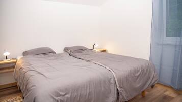 A bedroom with a bed, bedside lamps, and a window with curtains.
