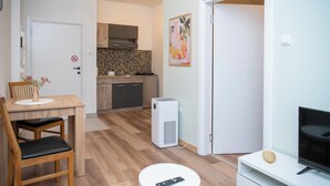 A compact living space with a dining area, kitchenette, and a TV on a stand. - Elegant apartment with Balcony & Free Parking (Subotica)