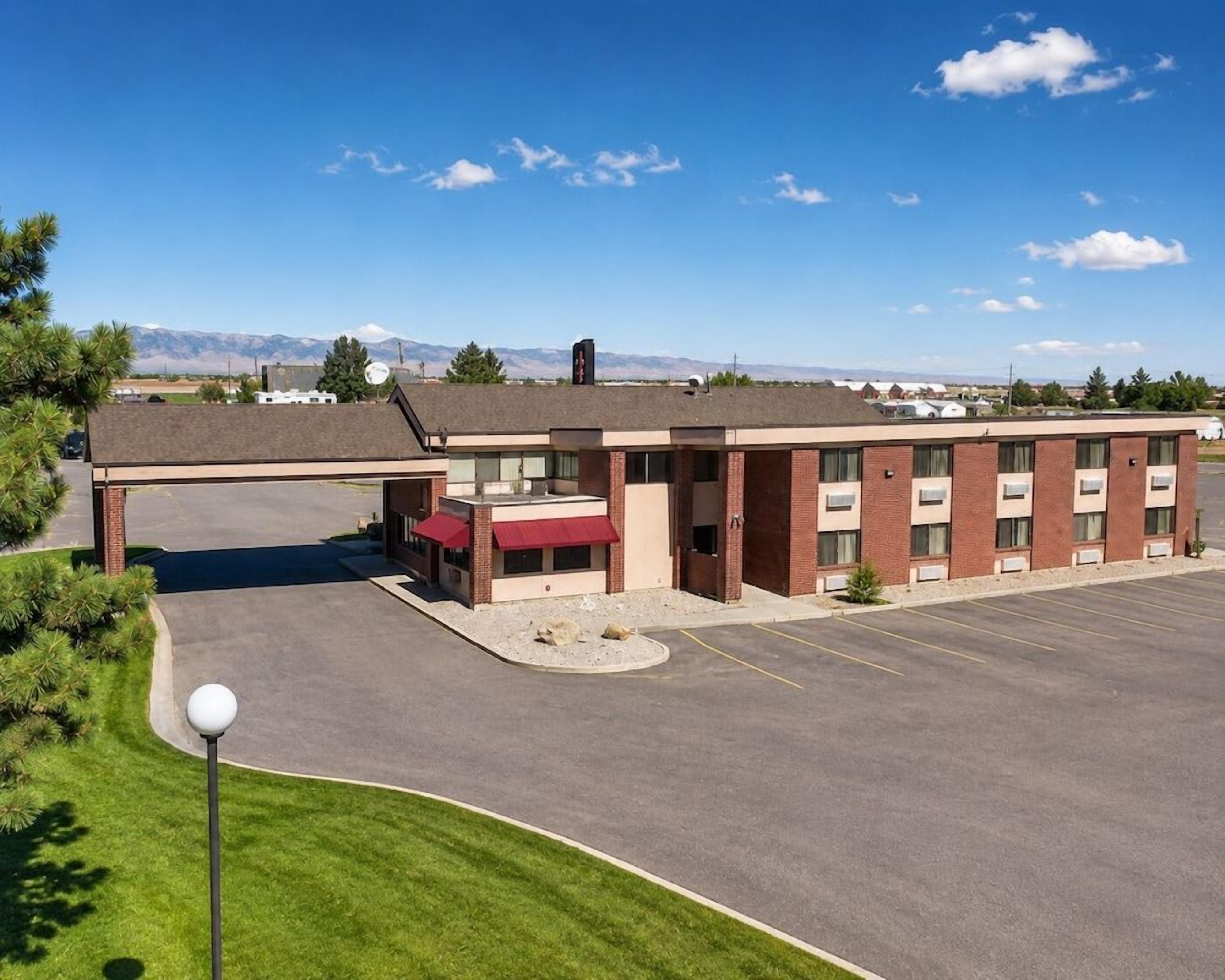 A multi-story hotel with a parking lot and a view of mountains in the background.