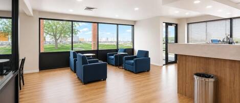 A modern office space with a reception desk, seating area, and large windows offering a view of the outdoors.