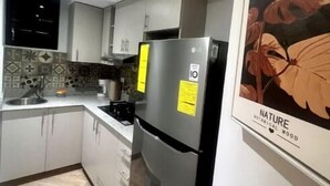 Una cocina moderna con armarios blancos, un refrigerador de acero inoxidable y un salpicadero de azulejos.