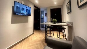 Una cocina moderna con una isla central, taburetes de bar y un televisor montado en la pared.