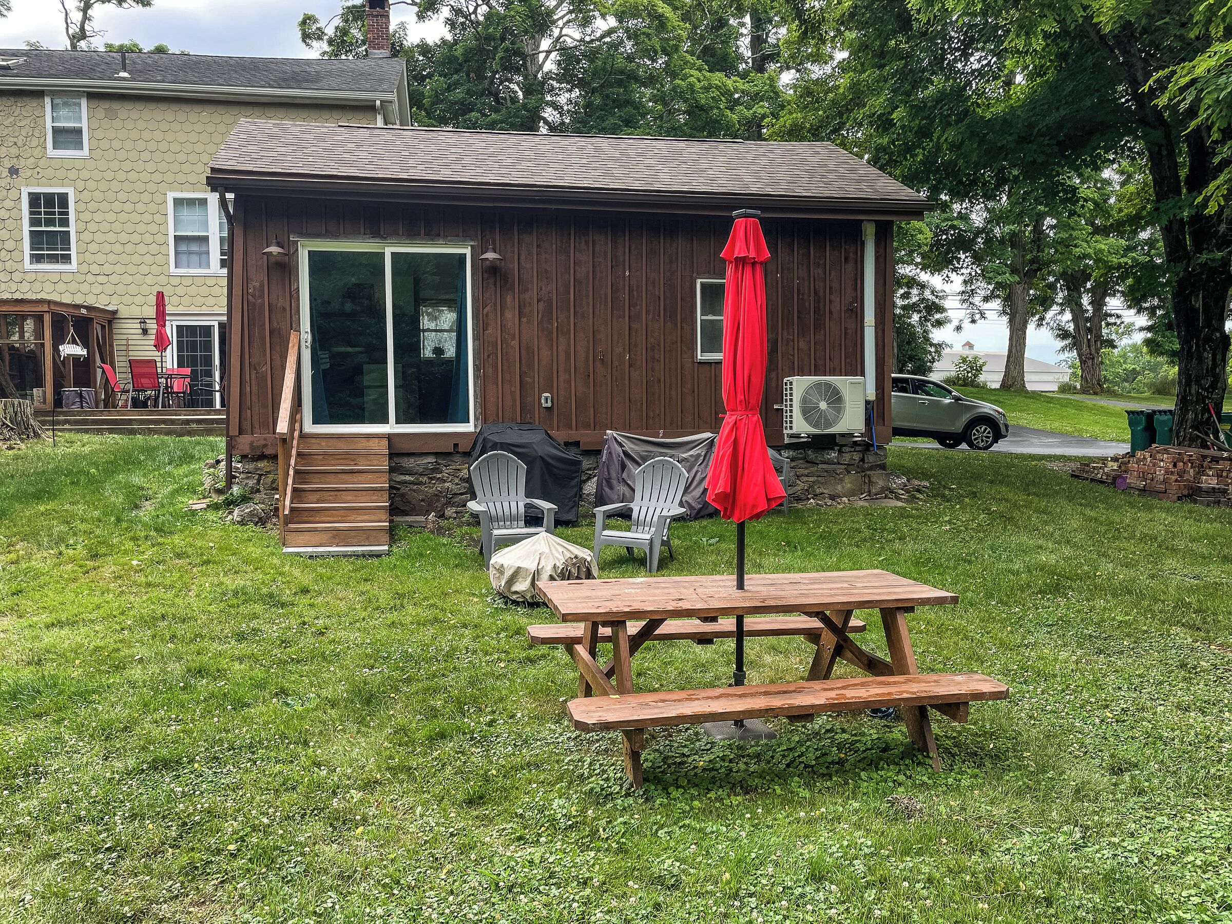 A wooden cabin with a patio area, outdoor seating, and a covered table.