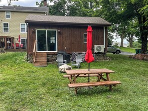A wooden cabin with a patio area, outdoor seating, and a covered table.
