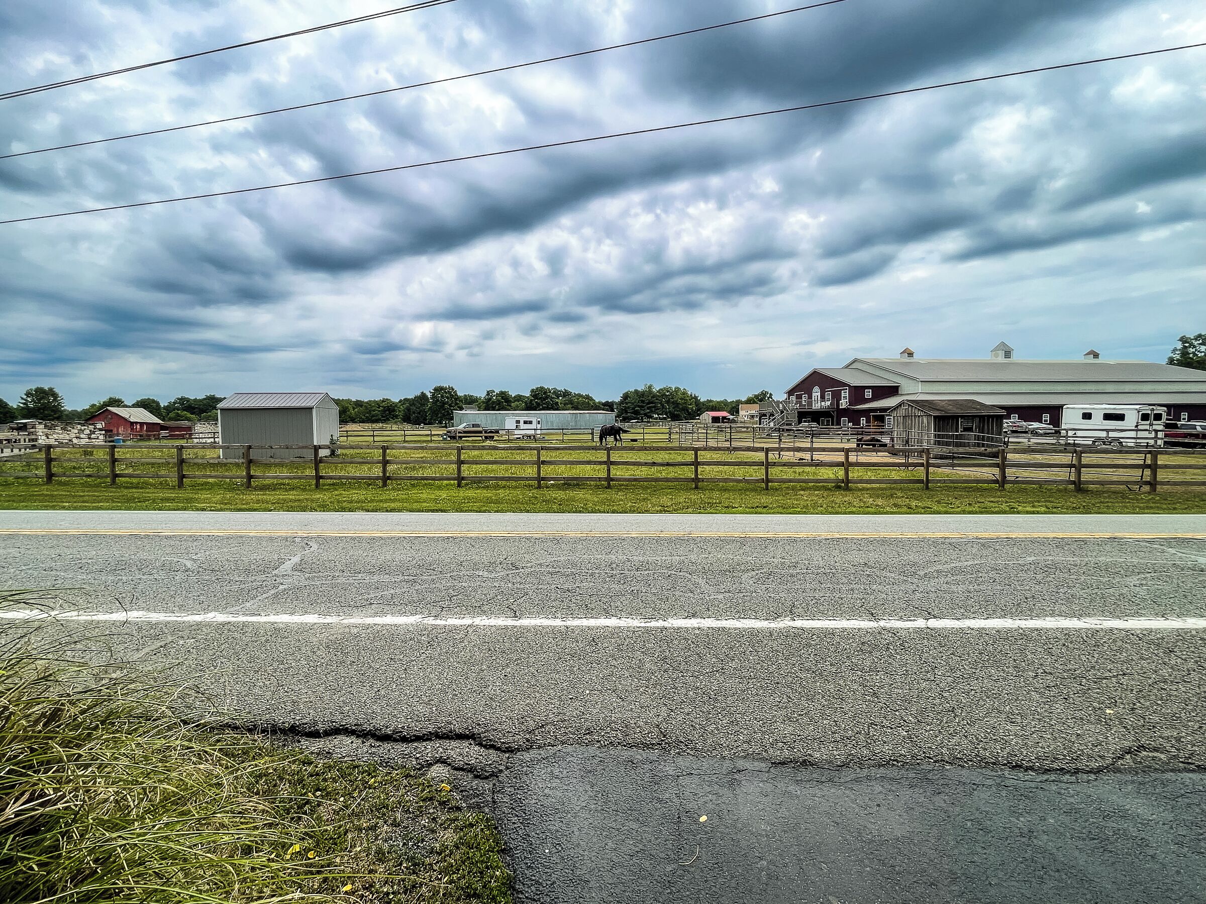 A rural landscape with a fenced property, a barn, and a road.
