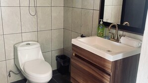A modern bathroom with a toilet, sink, and mirror. - Bungalows Garza Blanca a Pie de Playa (San Blas)