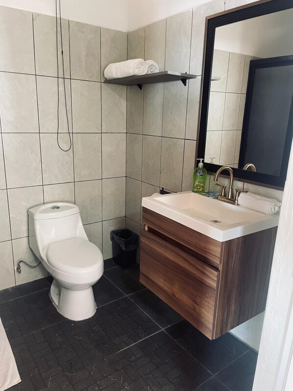 Un baño moderno con inodoro, lavamanos y espejo.