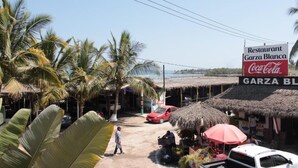 A restaurant named Garza Blanca with a Coca-Cola sign, surrounded by palm trees and thatched-roof structures. - Bungalows Garza Blanca a Pie de Playa (San Blas)