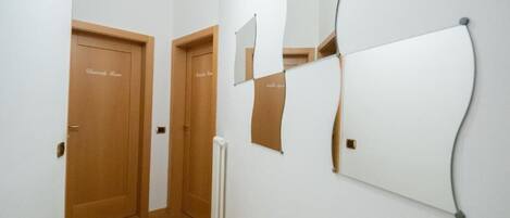 A hallway with two wooden doors labeled "Bedroom Room" and a white radiator on the wall.