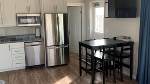 A modern kitchen with white cabinets, stainless steel appliances, and a wooden floor.