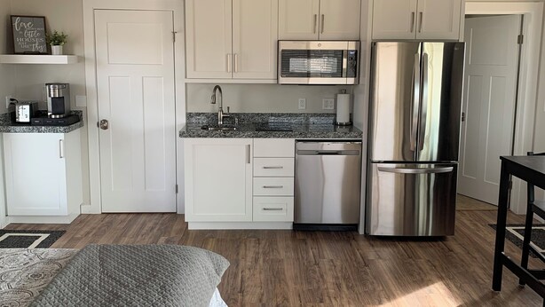 A compact kitchen with white cabinets, a stainless steel refrigerator, a microwave, and a coffee maker.