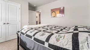 A bedroom with a bed, a door, and a painting on the wall. - The Magnolia Retreat (Omaha)