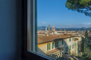 Vista urbana con una cúpula y una torre destacadas, vista a través de una ventana.