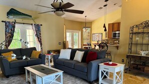 A living room with a grey sofa, two white coffee tables, and a ceiling fan. - Casa Palmera: 3 bedroom home (Sebastian)
