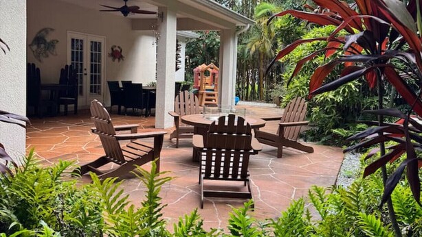 A covered patio with outdoor furniture, a play area, and lush greenery. - Casa Palmera: 3 bedroom home (Sebastian)