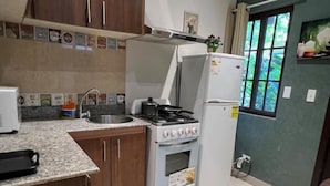 A kitchen with a gas stove, oven, sink, and a refrigerator.