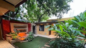 A courtyard with artificial grass, a fire pit, and potted plants.