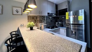 Una cocina moderna con encimeras de granito, un refrigerador de acero inoxidable y un salpicadero con diseño.