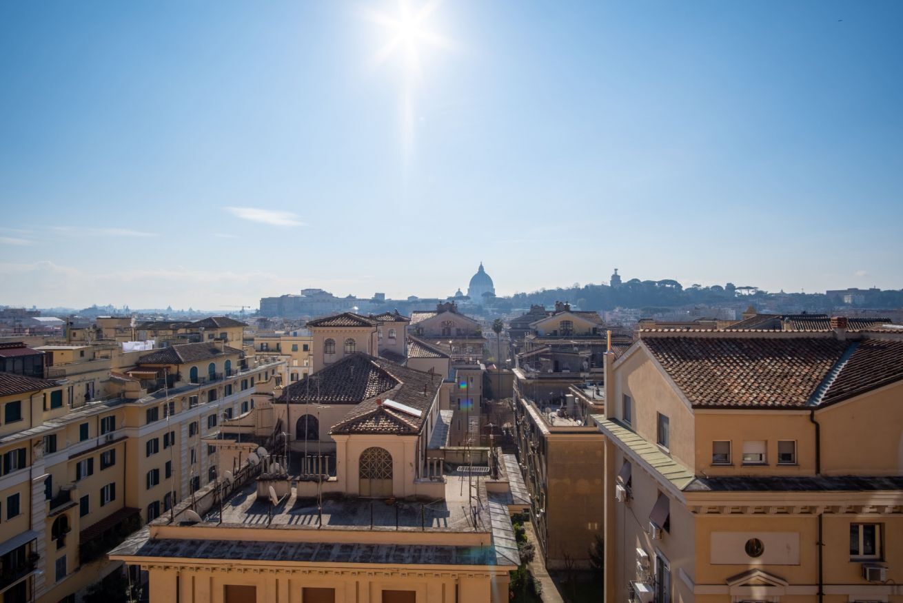 A cityscape with historic buildings and a prominent dome structure in the distance.