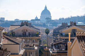A cityscape with historic buildings, a prominent dome structure in the background, and a clear sky.