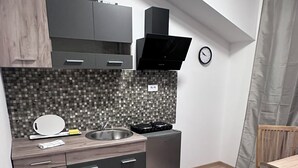 A compact kitchen with a modern design, featuring a built-in oven, a microwave, and a sink. - Cosy apartment close to the center, parking &WiFi (Subotica)