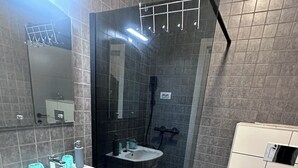 A modern bathroom with a glass-enclosed shower, a white sink, and a toilet. - Cosy apartment close to the center, parking &WiFi (Subotica)