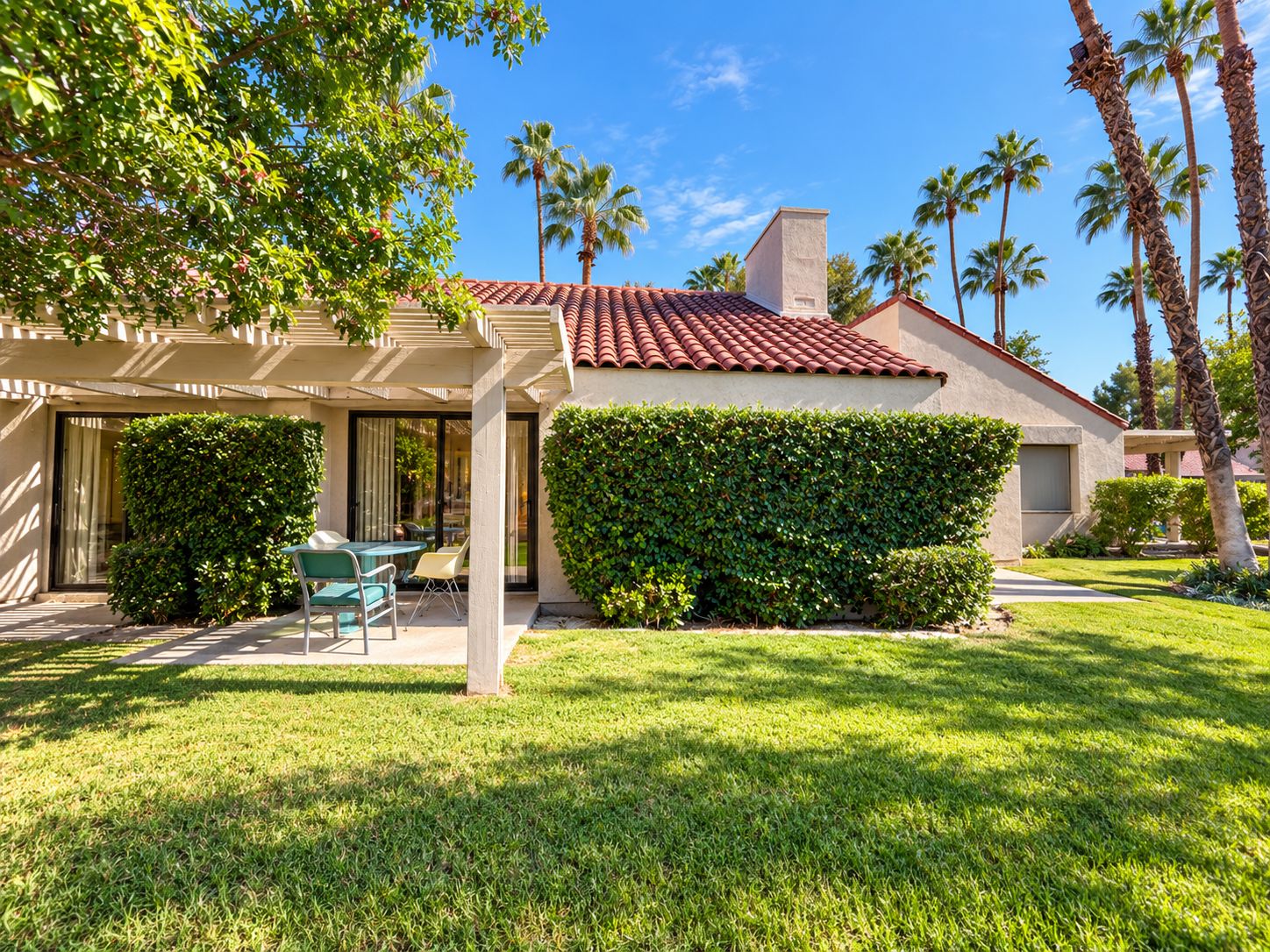 A residential property with a covered patio, a well-maintained lawn, and a clear sky.