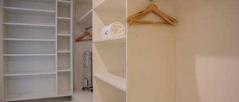 Un dressing avec de nombreuses étagères et un espace pour suspendre les vêtements, un appareil électroménager blanc et des cintres en bois.
