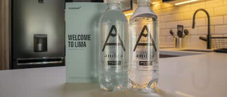 A welcome sign and two water bottles with labels in a modern kitchen setting.