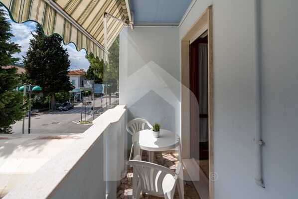 Enjoy a view of the street below from this balcony with a table and two chairs.