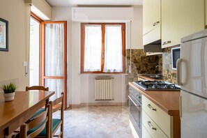 Una cocina con mesa, sillas, estufa y armarios.