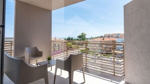 A balcony with two chairs and a table, overlooking a residential area with tiered buildings and a clear sky. - Holiday home Elea will give you a holiday in Pineto but with the charm of a new modern building, fresh and designed with all the comforts. The Dafne apartment is the only one on two levels of the entire Elea complex, at the entrance a large living room w (Pineto)
