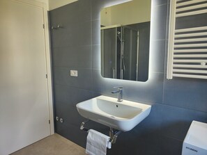 Bathroom features a pedestal sink and large mirror.