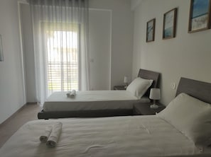 Two single beds with white linens and bedside tables with lamps.