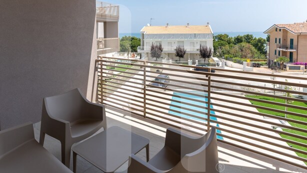 A balcony with outdoor furniture, a view of a pool, and buildings in the background. - Holiday home ELEA is the 2025 novelty that will give you a holiday in Pineto but with the charm of a new modern construction, fresh and designed with all the comforts. he Clio apartment has a large living room with kitchenette and sofa bed at the entranc (Pineto)