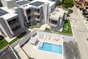 Un immeuble d’appartements moderne doté de nombreux balcons, d’une piscine sur le toit et de panneaux solaires.