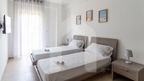 A hotel room with two single beds, a bedside table with a lamp, a TV mounted on the wall, and three framed pictures on the wall. - Holiday home ELEA is the 2025 novelty that will give you a holiday in Pineto but with the charm of a new modern construction, fresh and designed with all the comforts. The Calipso apartment has a large living room with kitchenette and sofa bed at the ent (Pineto)